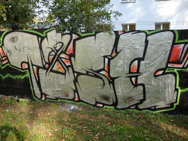 TASH chrome graffiti piece with green outline and pink orange accents on black background, park wall 2013