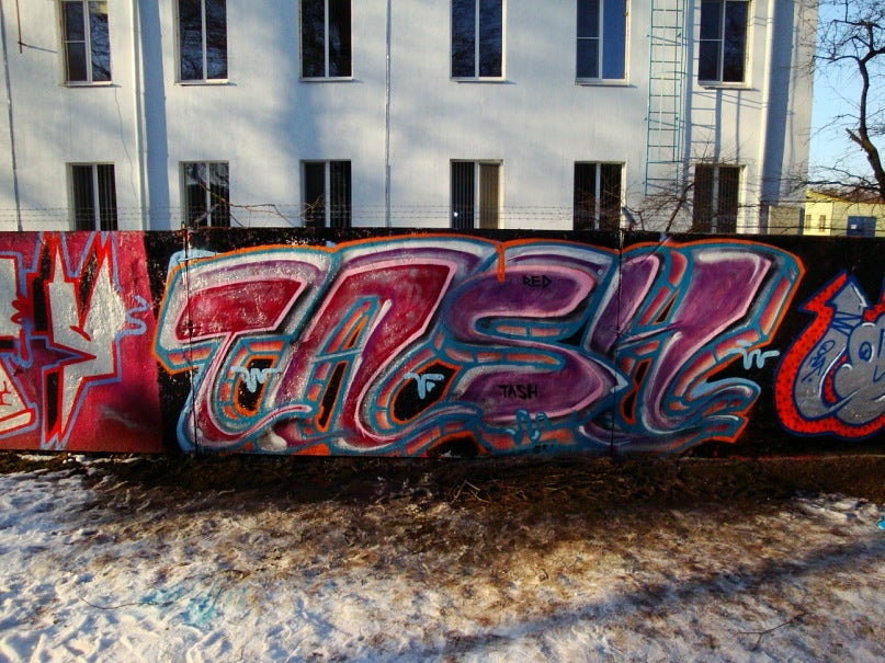 TASH and VISBY graffiti pieces on legal park wall in winter with snow on ground